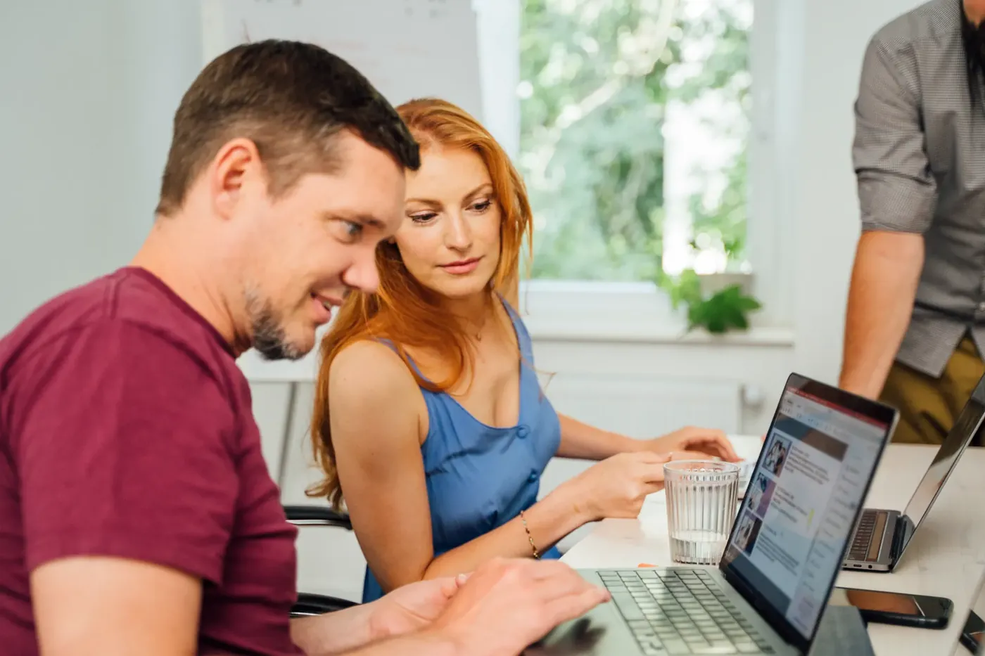 Zwei Personen moderieren gemeinsam die Kommentare eines Social-Media-Kanals am Laptop